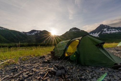 a green tent on a rocky beach